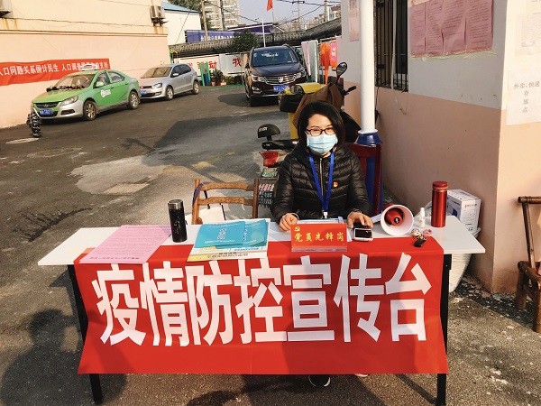 图4：井岗镇半岛新村社区工作人员在疫情防控宣传台值班。.JPG