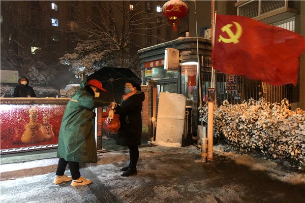 图1：社区工作人员在大雪中为进出小区人员测量体温.jpg