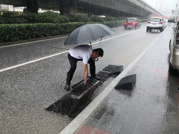 图3：井岗镇卫楼社区党员李占辉在雨中清理下水管道杂物.jpg